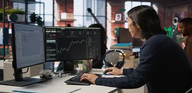 Woman working on multiple trading monitors